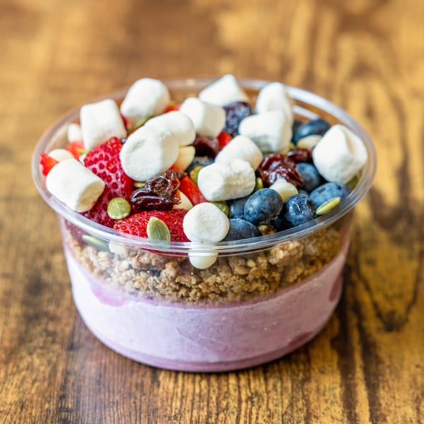 A colorful fruit and granola parfait with marshmallows, blueberries, strawberries, and pumpkin seeds.